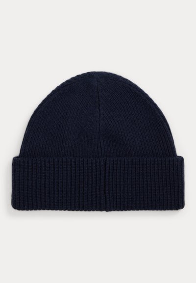 Bonnet tricoté bleu marine foncé avec un revers plié et une texture côtelée sur un fond clair.