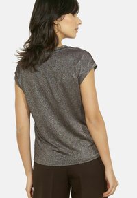 Top a maniche corte in tessuto grigio metallizzato scuro con una leggera brillantezza, caratterizzato da maniche arrotolate e una vestibilità morbida e rilassata.