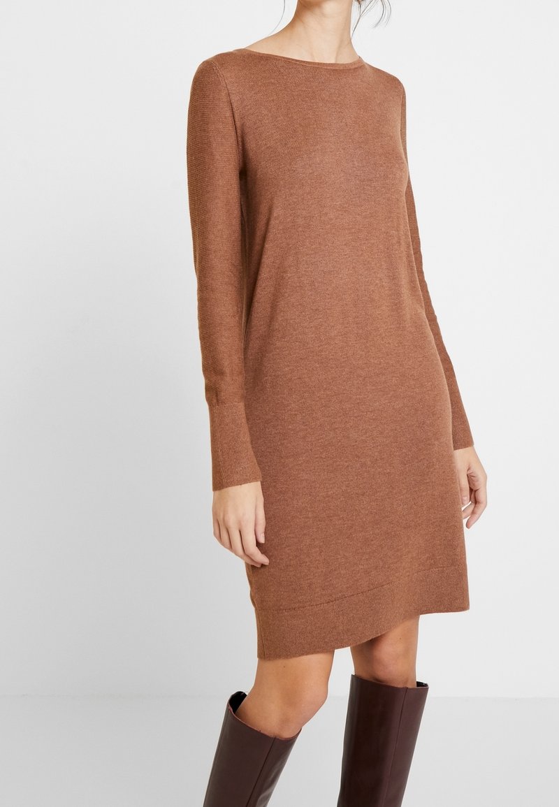 Robe en maille marron à manches longues, encolure bateau, longueur mi-cuisse, avec une texture côtelée ; complétée par des bottes marron mi-mollet.