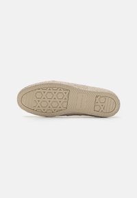 Sko sål med en tekstureret beige gummioverflade; har et geometrisk mønster og en let forhøjning nær tåområdet.