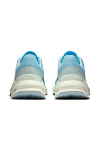 Des chaussures de sport bleu clair avec une tige texturée, une semelle rembourrée et des accents blancs sur la semelle et le talon. La vue de dos met en avant les détails de couture.