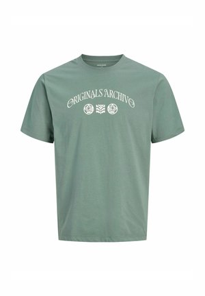 Sagegrøn t-shirt med korte ærmer med hvid tekst "Originals Archive" og tre cirkulære blomsterprints centreret på brystet.