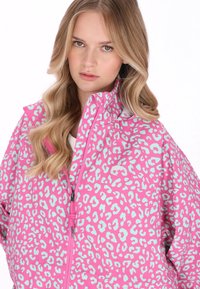 Růžová a tyrkysová bunda s gepardím potiskem, vysokým límcem, zapínáním na zip a volným střihem, vyrobená z lehké strukturované tkaniny.