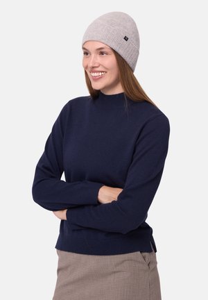 Navy knit sweater with a high neckline and ribbed cuffs, paired with a light gray fitted beanie featuring a small logo tag.