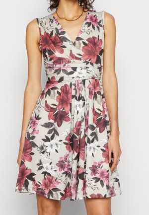 Sukienka w kwiaty w odcieniach różu i bieli na jasnoszarym tle. Posiada dekolt w serek, jest bez rękawów i ma dopasowaną talię.