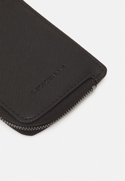 Portafoglio zippered nero con superficie testurizzata, dotato di un bordo superiore liscio e dettaglio di marca. Il materiale sembra resistente e elegante.