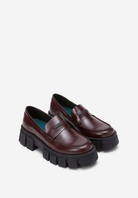 Brune læder loafers med en kraftig sort sål, prydet med detaljeret syning og en strop over fronten. Indersiden er foret med teal.