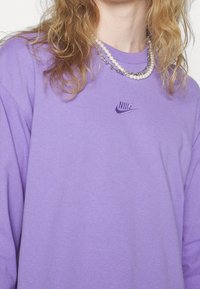 Lila långärmad sweatshirt med broderad Nike-logotyp på bröstet. Mjuk tyg med en avslappnad passform och rundad halsringning.