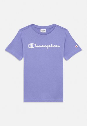 T-shirt violet à manches courtes avec un logo blanc Champion sur la poitrine et un petit emblème Champion sur la manche gauche.