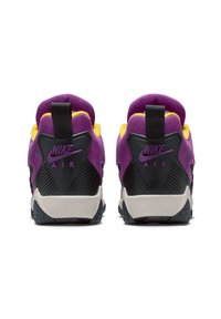 Lilla og gul sneakers med overdelen i nubuck, svarte detaljer og en teksturert hæl. Har en pull-tab og synlig Nike-logo.