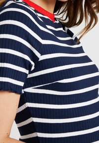 T-shirt w biało-niebieskie paski o ribbowanej fakturze, z czerwonym kołnierzykiem, krótkimi rękawami i dopasowanym krojem.