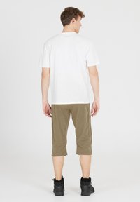 Vit t-shirt med kort ärm i kombination med olivgröna trekvartslånga byxor och svarta skor, med enkel design och avslappnad passform.