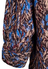 Langærmet beklædningsgenstand med et struktureret stof i en snoet mønster i sorte, blå og røde nuancer, med sammenkrøllede manchetter og en afslappet pasform.