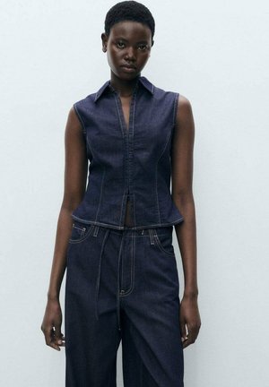Vest din denim cu design fără mâneci, culoare albastru închis, cusături detaliate, tiv peplum, asortat cu pantaloni largi din denim de aceeași culoare.