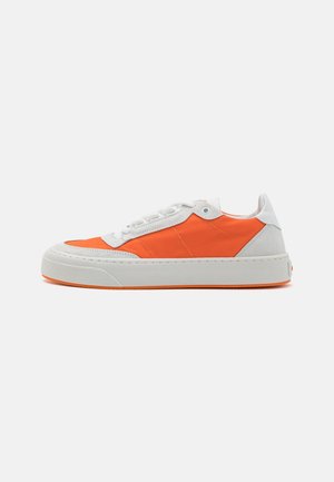 Zapatillas deportivas con parte superior de ante blanco y tela naranja, media suela blanca gruesa y suela exterior texturizada naranja. Se observan los cordones y los ojales.