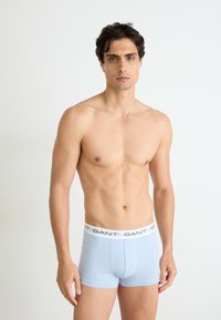Hellblaue Baumwollboxershorts mit einem weißen Bund, auf dem das "GANT"-Logo in Marineblau aufgedruckt ist. Der Schnitt ist eng anliegend und der Stoff hat eine glatte Textur.