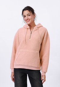 Ružičasta flis dukserica s polu-zip ovratnikom, velikim prednjim džepom i rebrastim rukavima. Mehak materijal i ležeran kroj povećavaju udobnost.