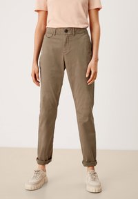 Chino khaki con un design a gamba dritta, dotati di chiusura a bottone, passanti per cintura e risvolti, abbinati a sneaker chiare.