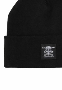 Beanie nero lavorato a maglia con orlo ripiegato, etichetta rettangolare con logo e testo, e superficie morbida e texture. Festival lo