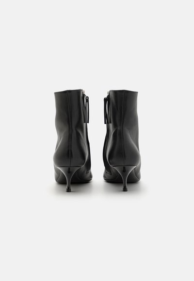 Botine negre din piele cu un design elegant, vârf ascuțit și toc stiletto de 3 inci. Prezintă fermoare la spate și o textură subtilă.