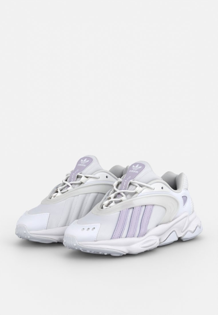 Scarpe sportive bianche con accenti viola chiaro, caratterizzate da una tomaia sintetica liscia, forma arrotondata e suola testurizzata con fori di ventilazione.