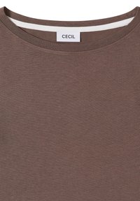 Chemise marron à col rond avec bande intérieure blanche au col et étiquette de marque "CECIL" cousue à l'encolure.