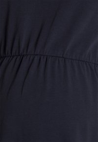 Tecido azul-marinho com uma textura suave, apresentando detalhes franzidos na cintura, criando um efeito de ondulação subtil.