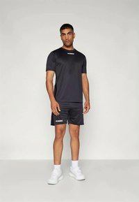 Black athletic t-shirt and shorts set, made of moisture-wicking material. Features white logo on the chest, with a relaxed fit and smooth texture.