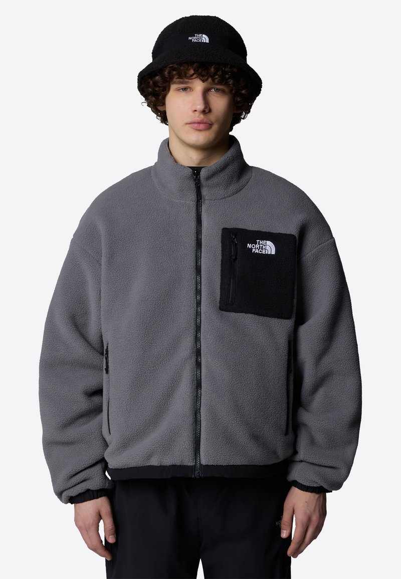 Gray fleece jacket with a black pocket, full zipper, high collar, and elastic cuffs. Accompanied by a matching black bucket hat.