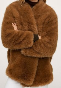 Brązowy płaszcz z imitacji futra o luźnym kroju, szerokich rękawach i bez guzików. Charakteryzuje się miękką fakturą oraz swobodnym, przytulnym designem.