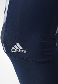 Marineblaue Sportleggings aus glattem Material mit dehnbarem Stoff und weißem Adidas-Logo am Unterschenkel.