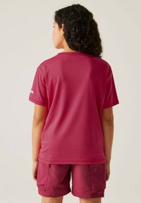 Camiseta atlética de manga corta en color burdeos, hecha de una tela suave, con cuello redondo y un corte holgado, acompañada de pantalones cortos a juego.