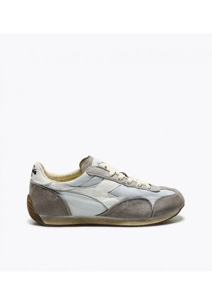 Sneaker in suede bianco e grigio a profilo basso con lacci beige e suola in gomma marrone, vista laterale.