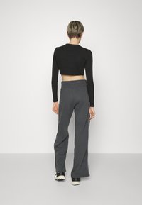 Cropped black top with long sleeves paired with gray wide-leg sweatpants featuring side stripes and a high waistband.