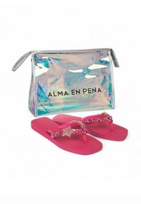 Chanclas rosas con un adorno en forma de estrella y piedras brillantes, acompañadas de un bolso transparente e iridiscente que contiene el texto "ALMA EN PENA."