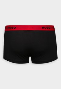 Schwarze Boxershorts aus weichem Stoff mit einem roten elastischen Bund, auf der Vorderseite mit dem schwarzen Logo "HUGO".