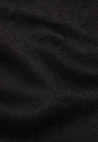 Närbild av slät svart tyg med fin stickad textur och mjuka veck.