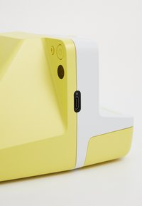 Yellow device with a geometric design featuring a white section, power button, indicator light, and a USB-C port. Smooth textured surface.