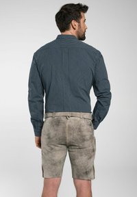 Gestreepte marineblauwe shirt met knoopmanchetten; lichtgrijze shorts met een gladde structuur, gele stiksels en zijzakken. Van achter bekeken.