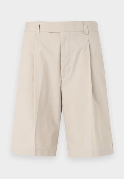 Μπεζ βερμούδες μέχρι το γόνατο με θηλιές για ζώνη, φερμουάρ μπροστά και μια πτυχία σε κάθε πόδι.