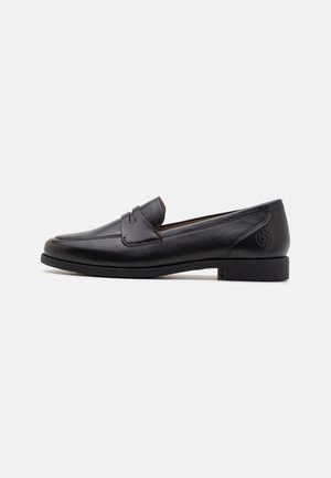 Mocassin noir en cuir sans lacets avec petit talon, bout arrondi, et un détail de lanière cousue sur le dessus, sur fond blanc uni.