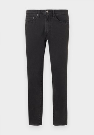 Schwarze Slim-Fit-Jeans mit Fronttaschen, Gürtelschlaufen und Knopfverschluss, auf einem neutralen hellen Hintergrund präsentiert.
