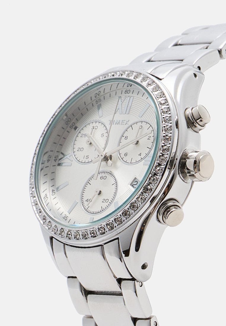 Orologio in metallo argento con quadrante rotondo, dettagli azzurri chiari, bezel scintillante e sottodial cronografico. Caratterizzato da un bracciale lucido.