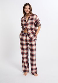 Conjunto de ropa de estar en cuadros en rojo, azul marino y crema; camisa de botones de manga larga con bolsillo y pantalones de pierna ancha a juego. Tejido texturizado, ajuste relajado.
