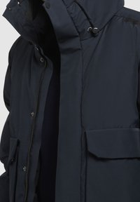 Granatowa ocieplana kurtka z zapięciem na zamek błyskawiczny i zatrzaski, wyposażona w kaptur, przednie kieszenie oraz gładką, lekko błyszczącą teksturę.