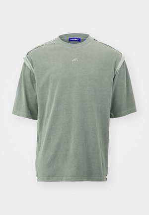 Pölyisen vihreä oversized lyhythihainen T-paita, jossa on paljaat reunat olkapäillä ja pieni valkoinen "A-COLD-WALL*" -logo rinnan keskellä.