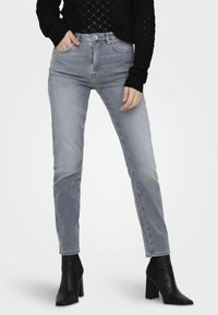 Světlé šedé džíny s vysokým pasem a klasickým střihem, s pěti kapsami, stříbrnými detaily a jemným vyblednutím podél stehen.