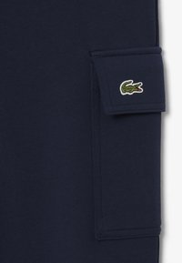 Marineblauwe sweatpants van katoen met een gestructureerde afwerking, voorzien van een zijzak en een groen geborduurd krokodillogo.