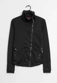 Schwarze Softshell-Jacke mit hohem Kragen. Verfügt über einen Frontreißverschluss, zwei seitliche Reißverschlusstaschen und ein geprägt detailiertes Logo an der Seite.