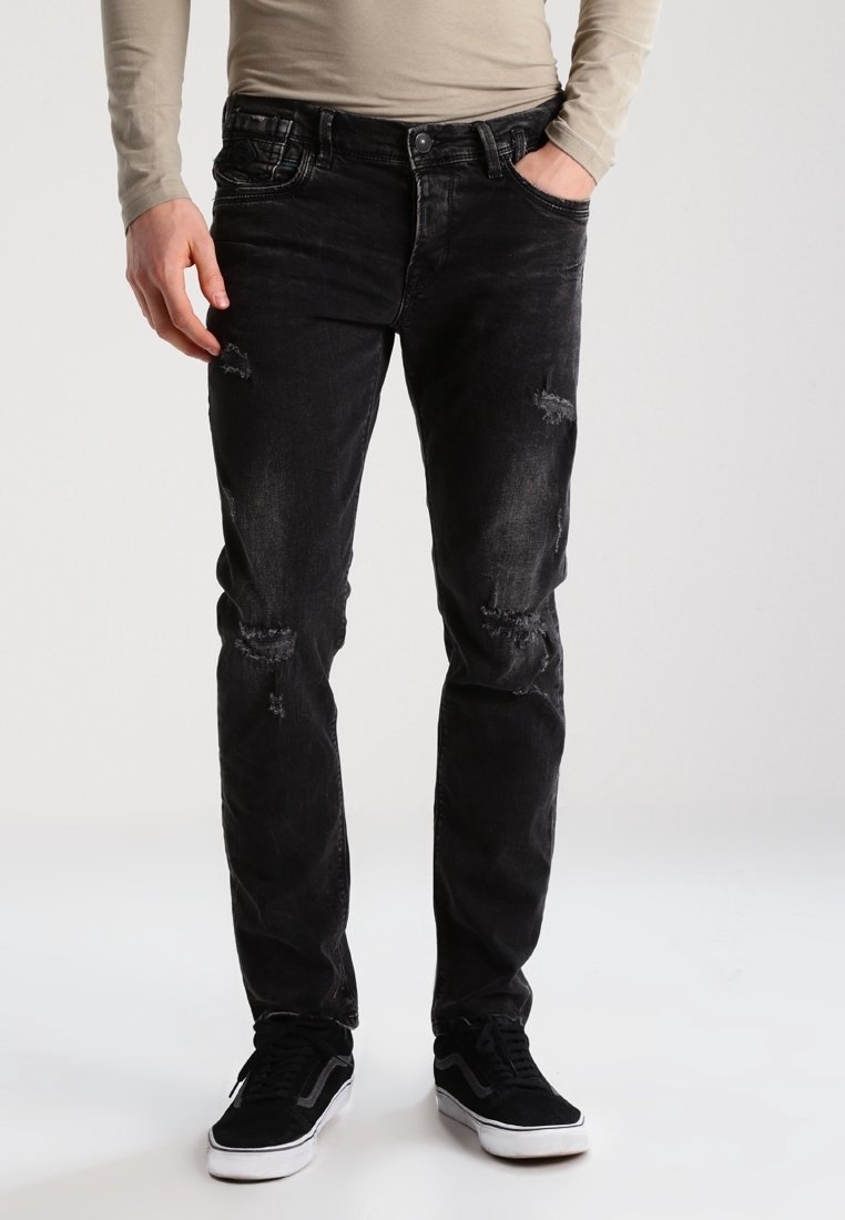 Svarta jeans i denim med blekningar, slitna detaljer och slim fit. I kombination med svarta sneakers. Långärmad tröja i neutrala toner.